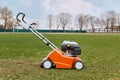 Mowing or cutting long grass with lawn mower. Gardening, taking care of sward. Side view of special equipment in field on