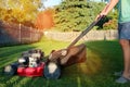 Mowing the grass with a lawn mower in sunny summer. Lawn mower season Gardener cuts the lawn in the garden.