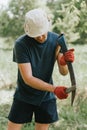 mowing grass traditional old-fashioned way with hand scythe on household village farm. young mature farmer man Royalty Free Stock Photo