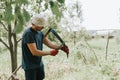mowing grass traditional old-fashioned way with hand scythe on household village farm. young mature farmer man Royalty Free Stock Photo