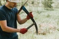 mowing grass traditional old-fashioned way with hand scythe on household village farm. young mature farmer Royalty Free Stock Photo