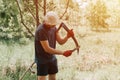 mowing grass traditional old-fashioned way with hand scythe on household village farm. young mature farmer Royalty Free Stock Photo