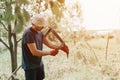 mowing grass traditional old-fashioned way with hand scythe on household village farm. young mature farmer Royalty Free Stock Photo