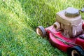 Mowing a lawn with a old style petrol gasoline lawnmower. Red lawn mower cutting grass . Gardening concept background Royalty Free Stock Photo
