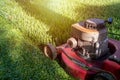 Mowing a lawn with a old style petrol gasoline lawnmower. Red lawn mower cutting grass . Gardening concept background Royalty Free Stock Photo