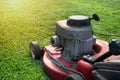 Mowing a lawn with a old style petrol gasoline lawnmower. Red lawn mower cutting grass . Gardening concept background Royalty Free Stock Photo