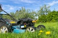 Mowing lawns. Lawn mower on green grass. Mower grass equipment. Mowing gardener care work tool. Close up view. Sunny day. Soft lig Royalty Free Stock Photo