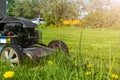 Mowing lawns. Lawn mower on green grass. Mower grass equipment. Mowing gardener care work tool. Close up view. Sunny day. Soft lig Royalty Free Stock Photo