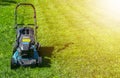 Mowing lawns, Lawn mower on green grass, mower grass equipment, mowing gardener care work tool, close up view, sunny day. Soft lig