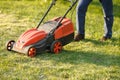 Mowing trimmer - worker cutting grass in green yard at sunset. Man with electric lawnmower, lawn mowing. Gardener Royalty Free Stock Photo