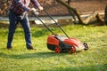 Mowing trimmer - worker cutting grass in green yard at sunset. Man with electric lawnmower, lawn mowing. Gardener Royalty Free Stock Photo