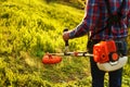 Mowing trimmer - worker cutting grass in green yard at sunset Royalty Free Stock Photo