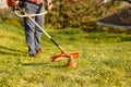 Mowing trimmer - worker cutting grass in green yard at sunset Royalty Free Stock Photo