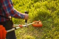 Mowing trimmer - worker cutting grass in green yard at sunset. Royalty Free Stock Photo