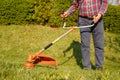 Mowing trimmer - worker cutting grass in green yard at sunset Royalty Free Stock Photo