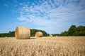 On  mown grain field lie round pressed bales of straw and the sky is blue Royalty Free Stock Photo