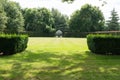 Mown lawn and trimmed hedges in garden with white steel gazebo in distance Royalty Free Stock Photo