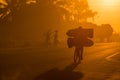 A Mozambican cyclist carrying large bags of coal to market at sunrise