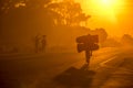 A Mozambican cyclist carrying large bags of coal to market at sunrise