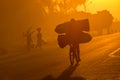 A Mozambican cyclist carrying large bags of coal to market at sunrise