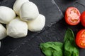 Mozzarella cheese, basil tomato cherry over old black backgroundon black stone slate   close up Royalty Free Stock Photo