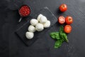 Mozzarella cheese, basil tomato cherry over old black backgroundon black stone slate space for text