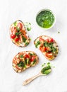 Mozzarella cheese, cherry tomatoes and arugula pesto bruschetta on light background, top view. Arugula pesto and sandwiches - tast Royalty Free Stock Photo