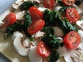 Mozzarella, spinach, mushroom and tomato topped pizza