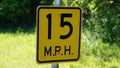 A 15 MPH sign on a country road for a sharp corner.