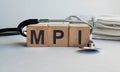 MPI inscription on wooden cubes isolated on white background, medicine concept. A stethoscope and protective masks are on the Royalty Free Stock Photo