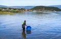 A black boy draws water in a blue basin from Lake Tanganyika