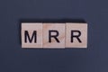 MRR short for Monthly Recurring Revenue from wooden letters on a gray background