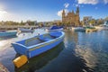 Msida, Malta - Blue traditional fishing boat with the famous Msida Parish Church Royalty Free Stock Photo