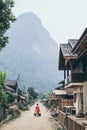 Muang Ngoi, Laos - May 2019: Laotian woman with two buckets walking on the central street of the village