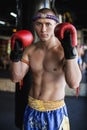 Muay thai fighter standing with hands on red gloves at gym