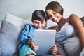 So much fun. an adorable little boy and his pregnant mother using a laptop while relaxing on her bed. Royalty Free Stock Photo