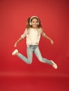 So much fun. Girl listening music modern gadget. Kid happy with wireless headset dancing jumping. Stereo headphones. Kid