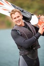 This is so much fun. Smiling water-skier holding his skis alongside the lake. Royalty Free Stock Photo