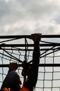 Mud race runners, defeating obstacles by using ropes. Details of the hands