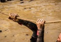 Mud race runners, defeating obstacles by using ropes. Details of the hands