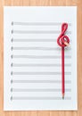 Blank sheet music end a red pencil in the shape of treble clef. Composing concept.