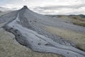 Mud volcano eruption in arid land with grey clouds in background Royalty Free Stock Photo