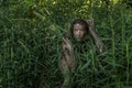 Muddy Amazon girl hiding behind a bush in the woods