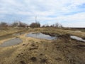 Muddy county road with puddles, pools, plashes, slops, hags. Countryside. Royalty Free Stock Photo