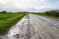 Muddy dirty rural gravel road with puddles of water after rain
