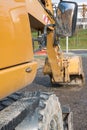 Muddy excavator shovel with rear-view mirror at construction are