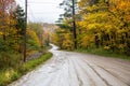 Muddy mountain road through a a deciduous forest on a rany day in autumn