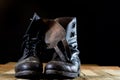 Muddy old military boots. Black color, dirty soles. Wooden table Royalty Free Stock Photo