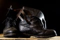 Muddy old military boots. Black color, dirty soles. Wooden table Royalty Free Stock Photo