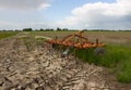 Muddy red harrow at the edge of the field, used by the farmer. Royalty Free Stock Photo